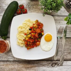Semoule aux légumes d’été épicés et œufs sur le plat